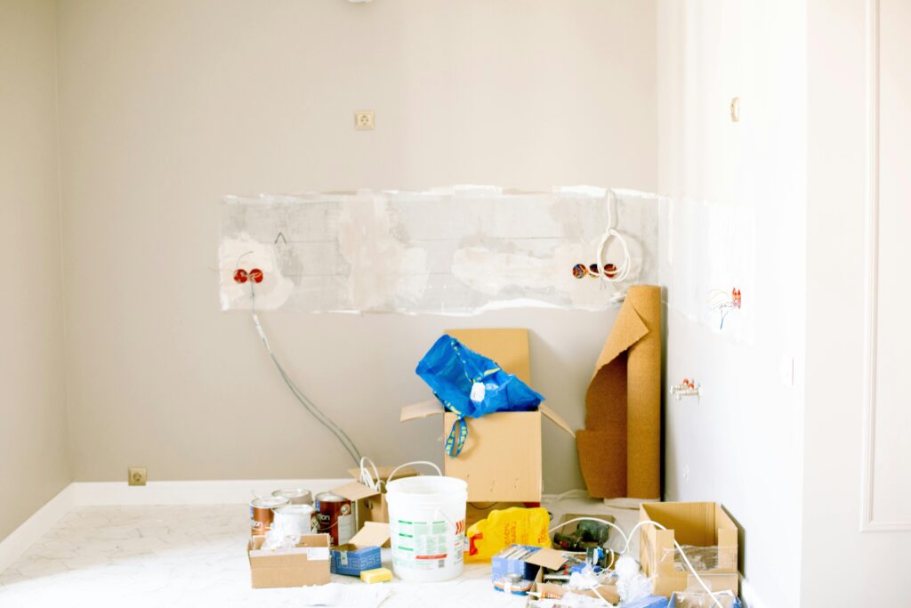 A room undergoing renovation with tools, supplies, wiring, and paint cans scattered around.