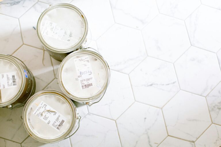 Aerial view of paint cans on a hexagonal tile floor, perfect for renovation themes.