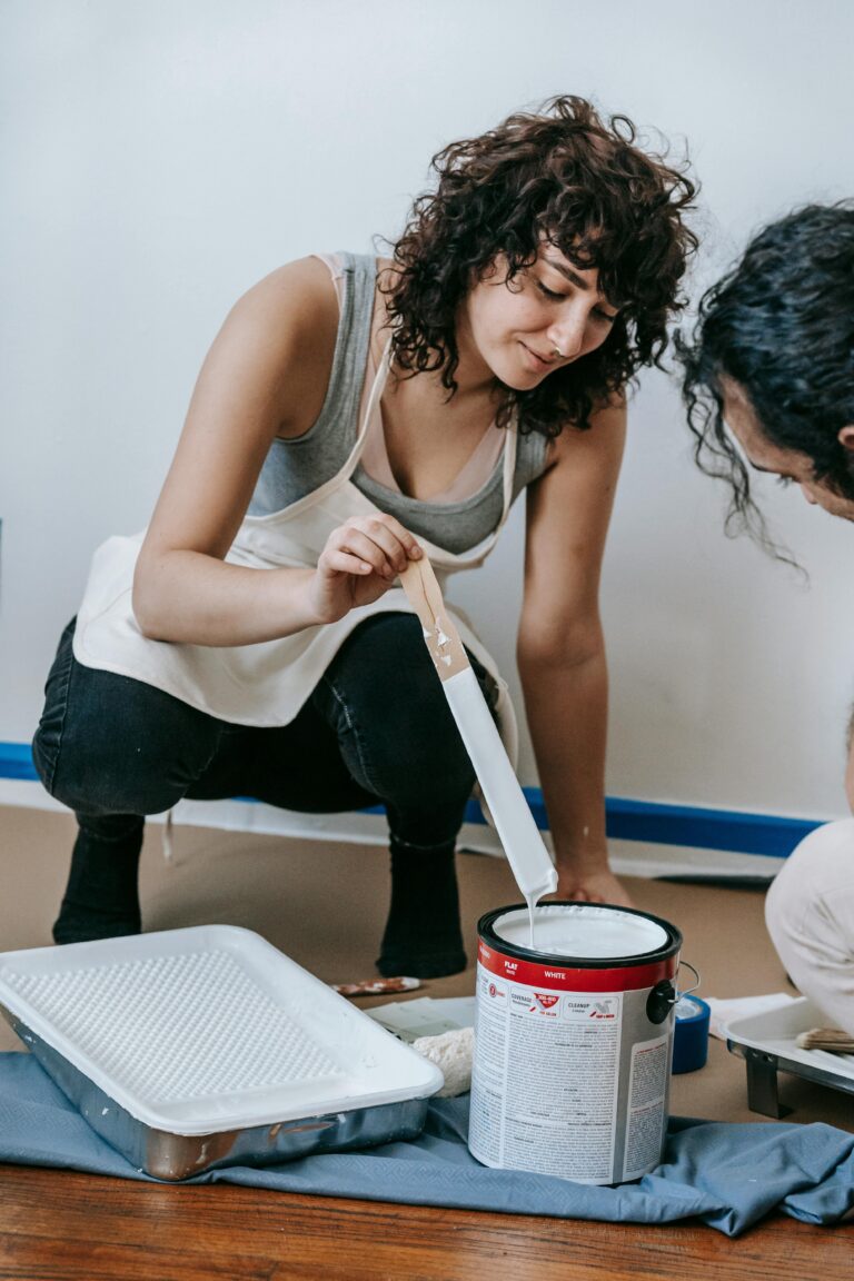 A couple working together on a home painting project, mixing paint indoors for renovation.