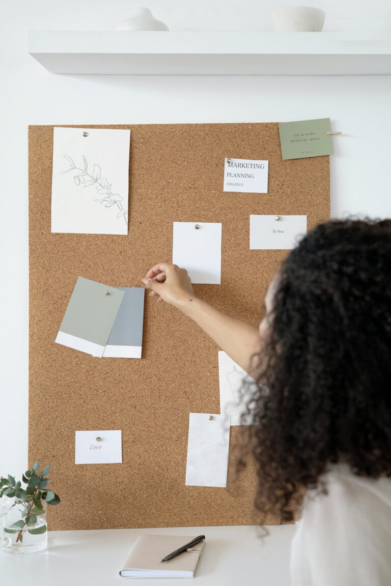 A woman arranges a mood board with design samples in a stylish, minimalist office environment.